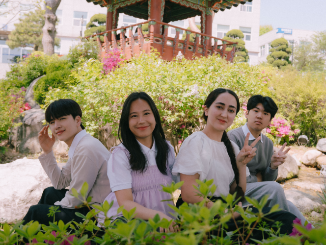 다양한 국적의 학생 셋이 도서관 테이블에 앉아 한국어 선생님에게 수업을 듣는 모습을 담은 사진